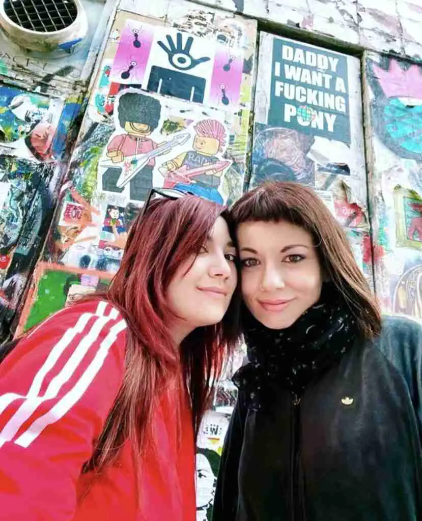 Marzia Parmigiani and Elina Sindoni in Brick Lane London in front street art wall - How to be happy