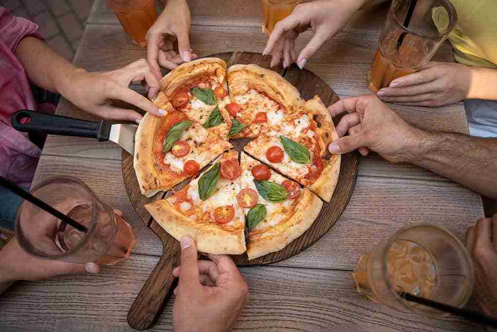 hands sharing slices of pizza