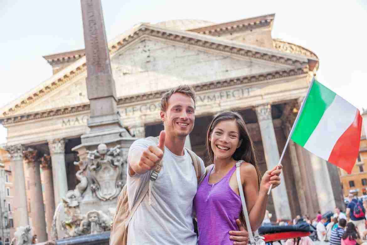 young couple visiting Rome smiling with italian flag