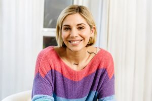 Christina Perri smiling in a casual portrait wearing a colorful sweater