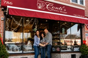 The exterior of Conti's Pastry Shoppe in Morris Park, Bronx, with Safet Paljevic, Senada Paljevic, and Christina DiRusso standing outside the historic Italian-American bakery.